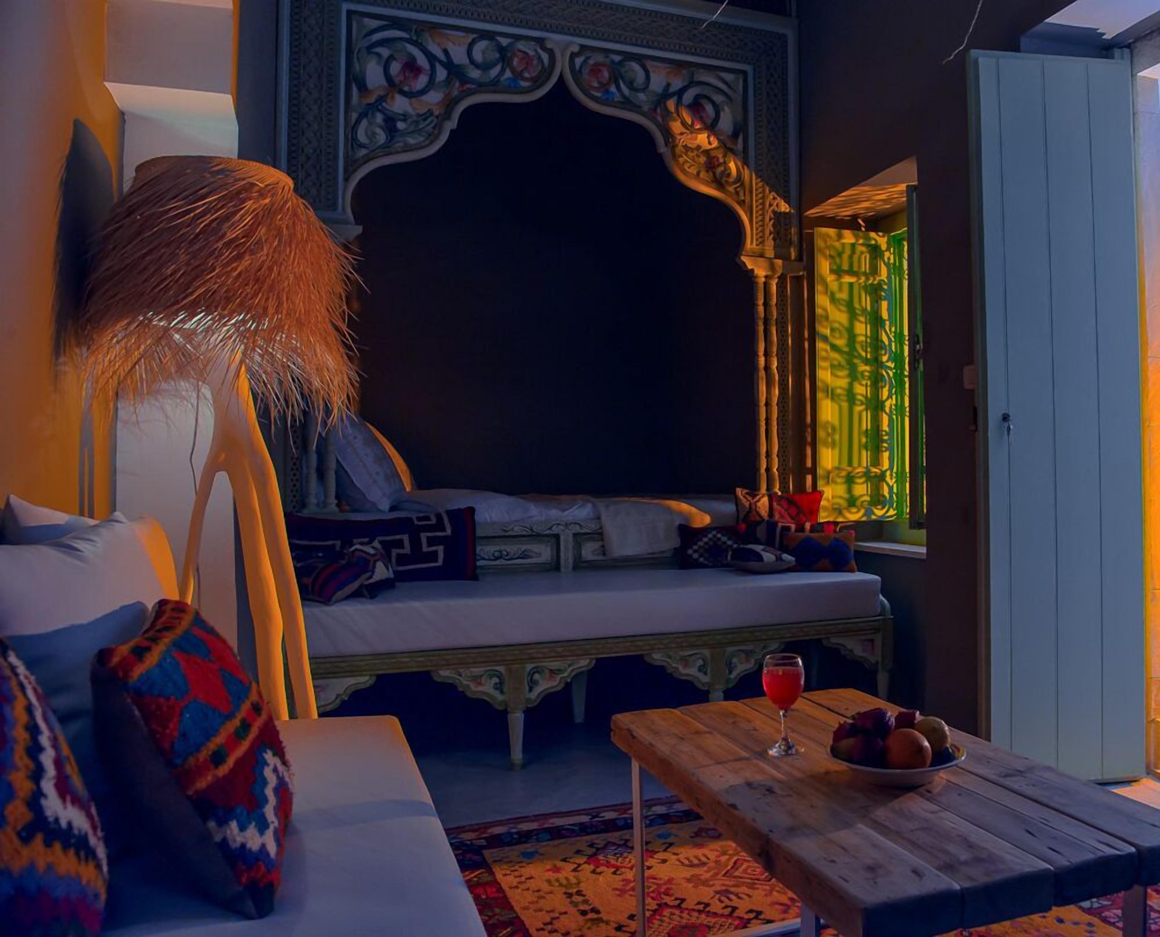 A cozy room with a bed, a table with a drink and fruit, and a decorative wall.