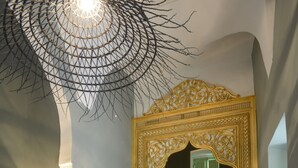 Ett modernt badrum med en stor spegel, ett handfat i en träskål och en unik taklampa.