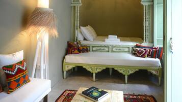 A room with a bed, a sofa, a lamp, a coffee table, and a patterned rug.