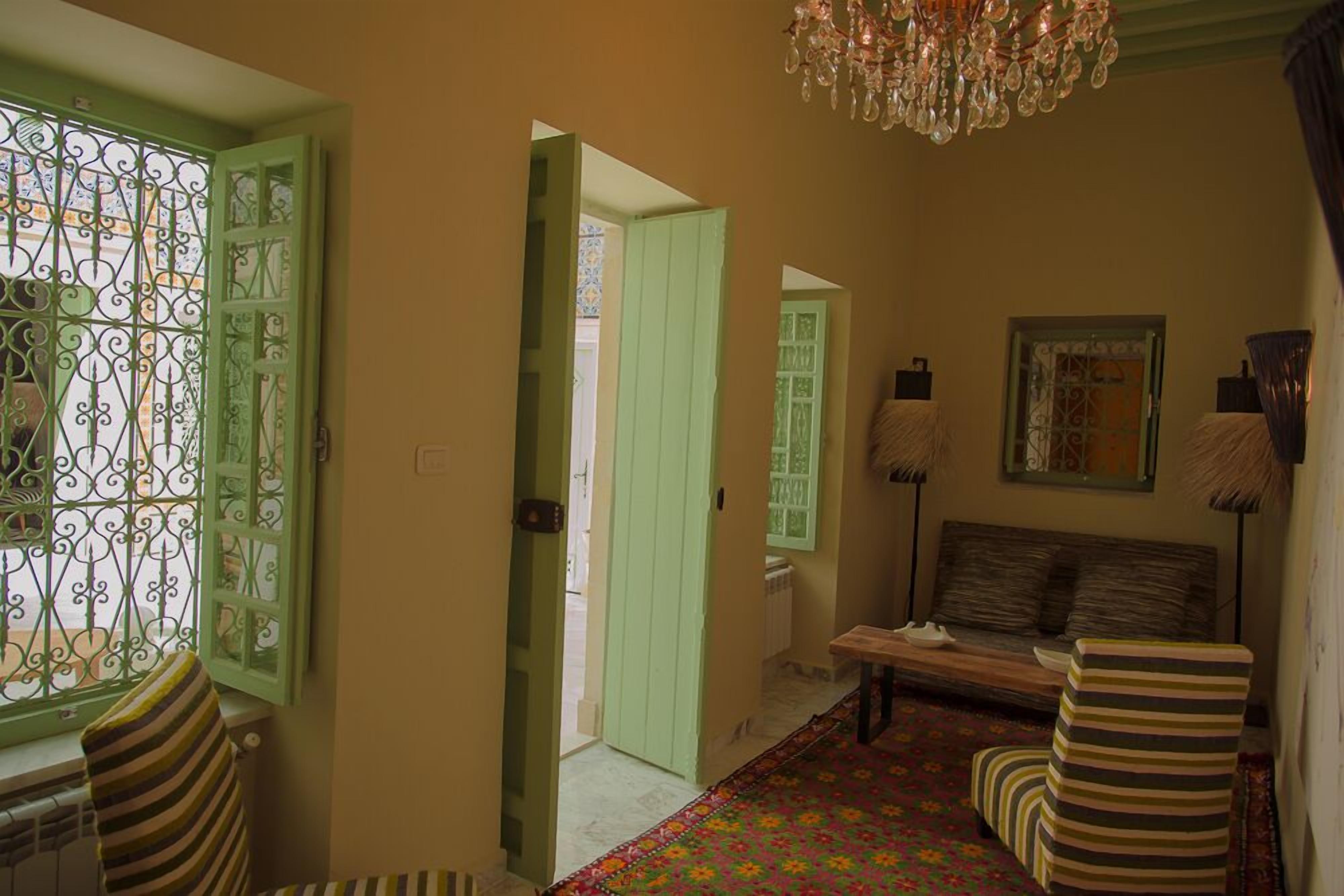 A hallway with a bench, a patterned carpet, and a chandelier.
