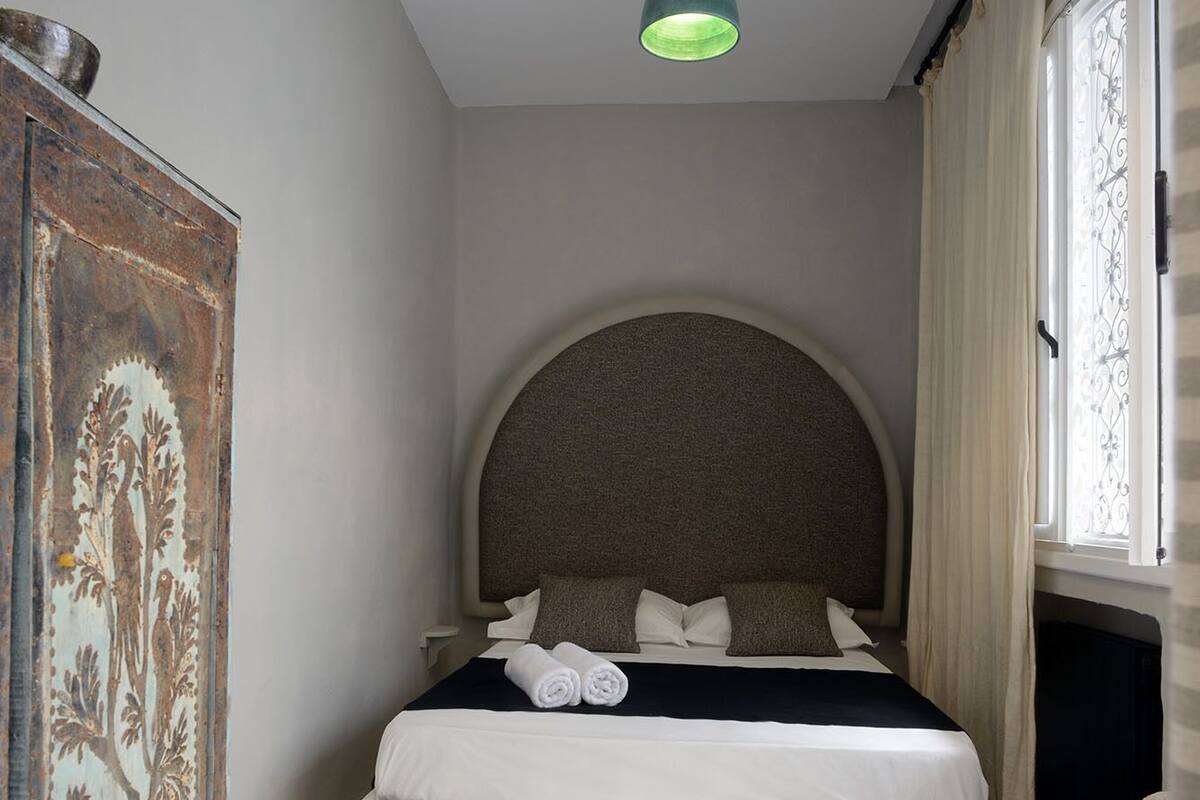 A bedroom with a bed, a chair, a desk, and a decorative wall piece.
