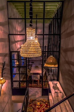Een trap met een hanglamp met patroon en een uitzicht op een eetgedeelte met een tafel en stoelen.