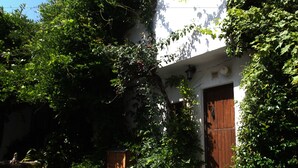 A courtyard with a stone pathway, potted plants, and a wooden door. - Fundalucia (Quentar)