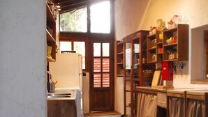 A kitchen with a refrigerator, wooden cabinets, and a dining area with a table and chairs. - Fundalucia (Quentar)