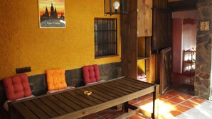 A wooden bench with cushions, a stone wall, a window with bars, and a poster on the wall. - Fundalucia (Quentar)