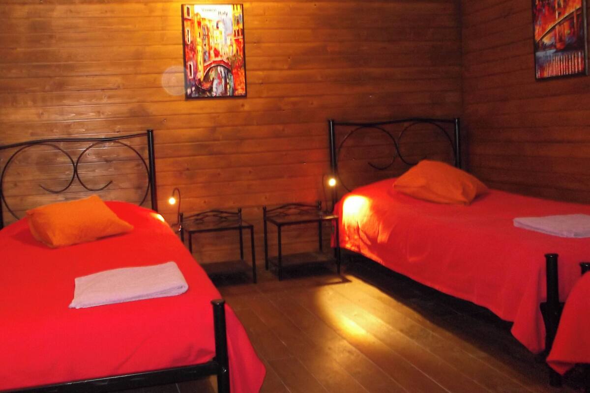 Habitación con dos camas, paredes de madera y un cuadro de Venecia.