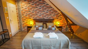 Une chambre avec un mur en briques, un plafond de style industriel et un lit avec deux serviettes blanches.