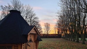 Une cabane en bois avec un toit en pente, un petit porche et une fenêtre à motifs triangulaires.