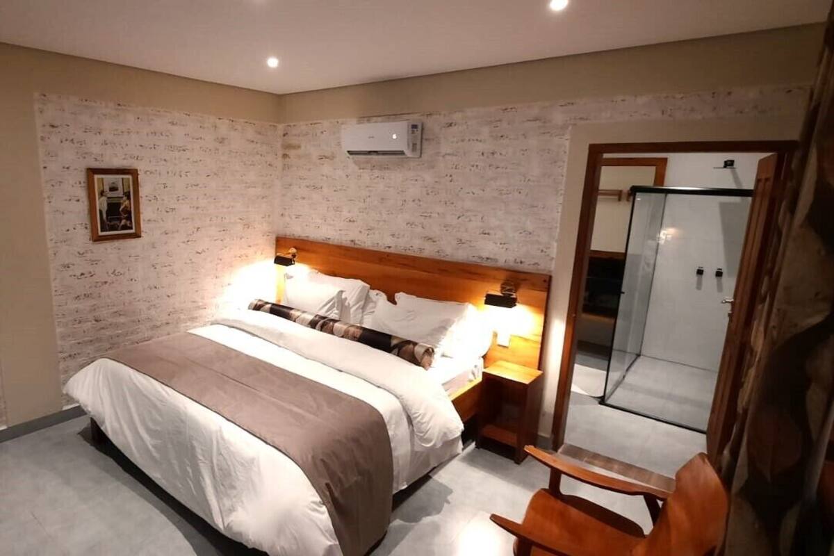 Un dormitorio con cama, lámparas de noche, cabecero de madera, espejo y armario.
