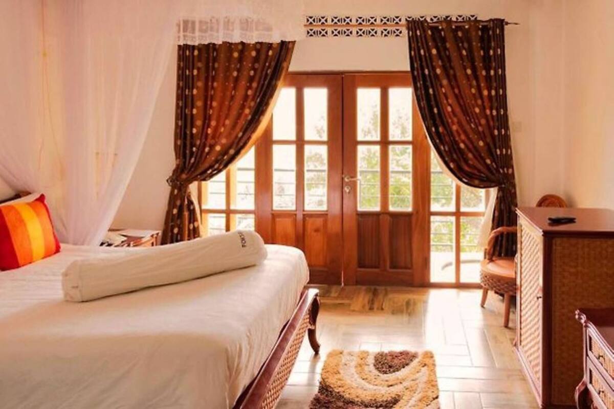 Quarto com cama, cortinas, janela e uma cadeira.