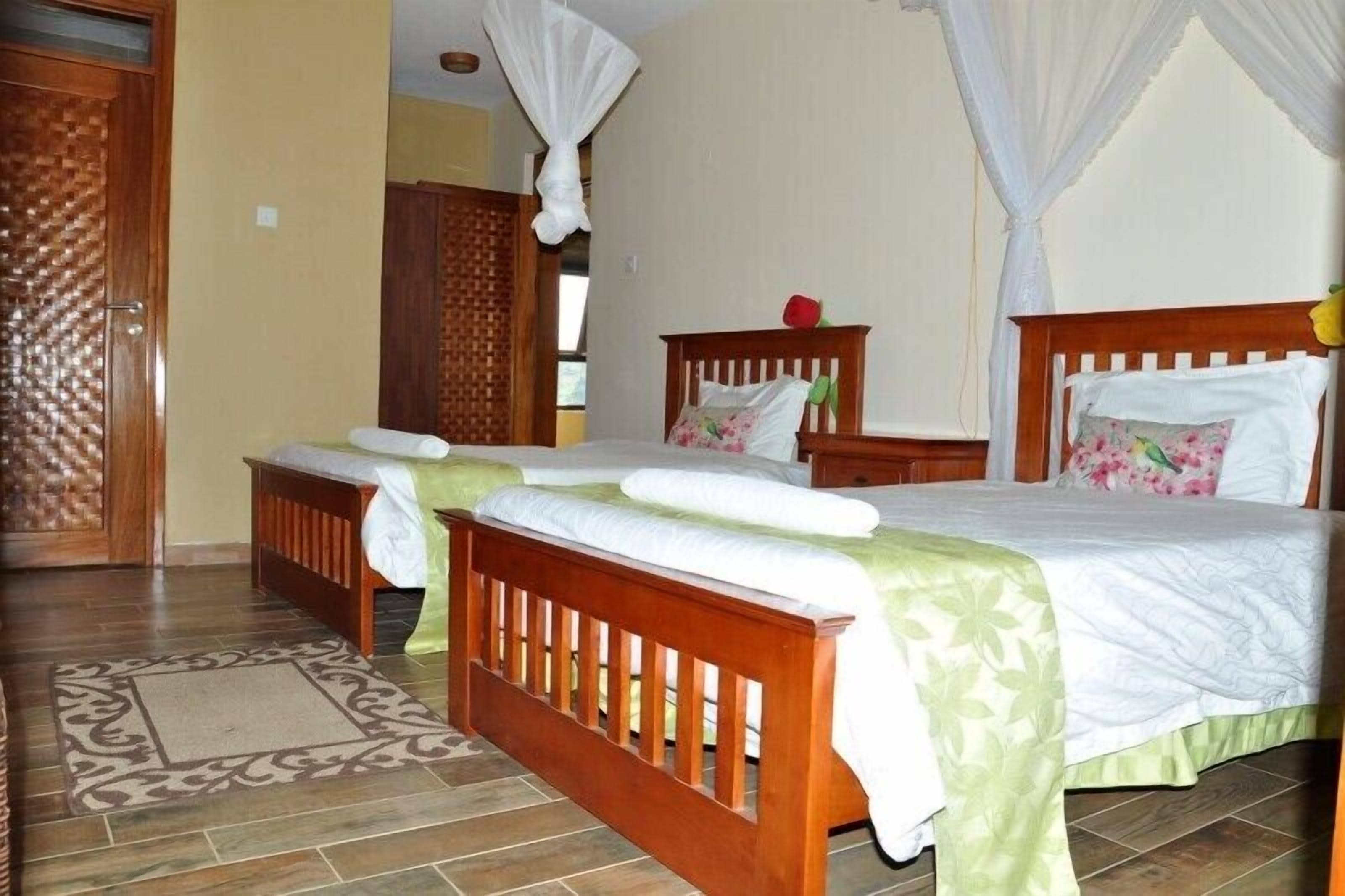 A bedroom with two wooden beds, a small bedside table, and a decorative wall panel.