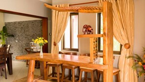 Una mesa de comedor de madera con sillas, un banco de madera y una figura decorativa de elefante.