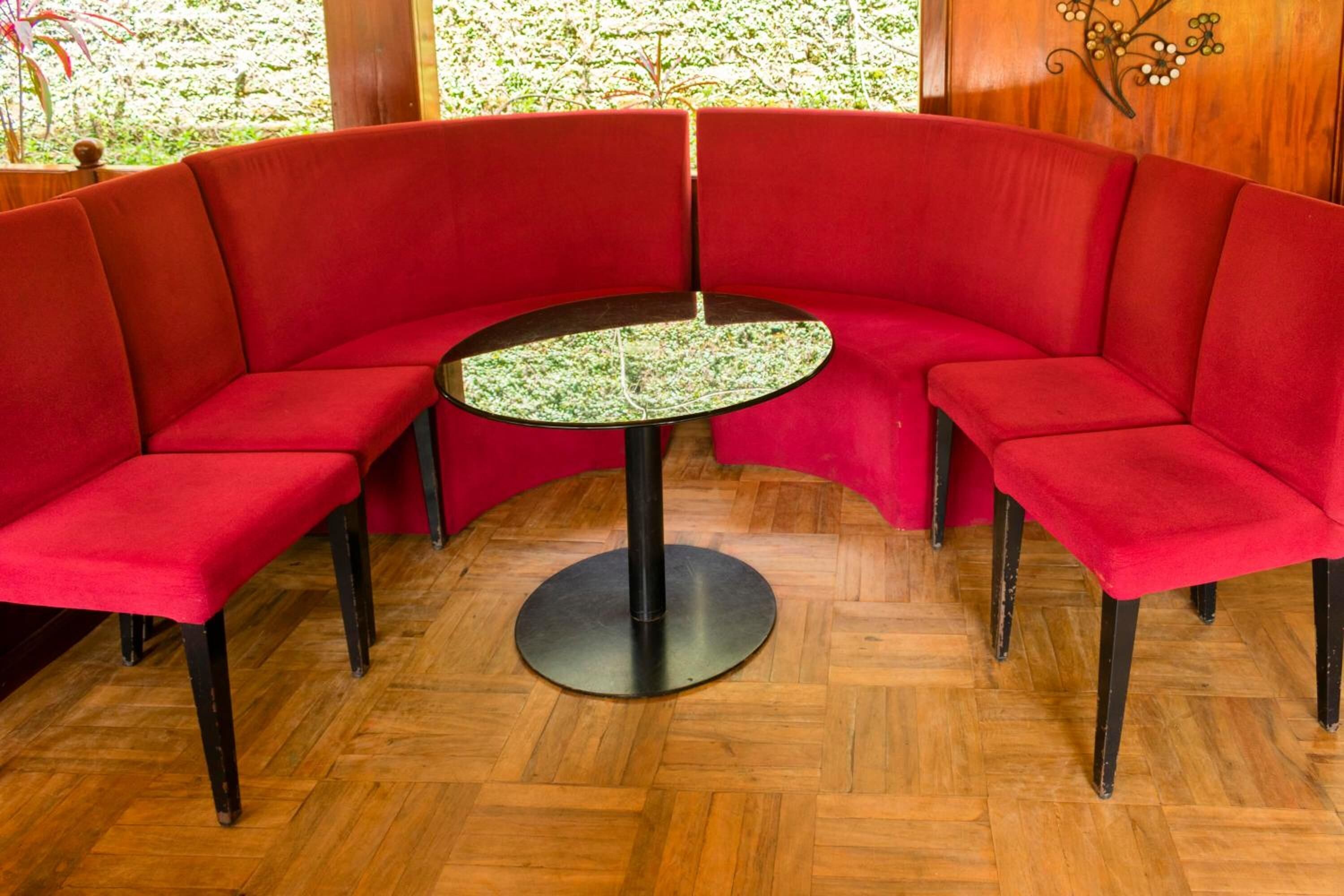 A red upholstered booth with a round table in the center.
