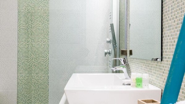 A bathroom with a white sink, a mirror, and a shower area with a glass door.