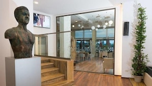 Un interior moderno con una escalera, una puerta de cristal que da a un comedor y una planta en maceta.