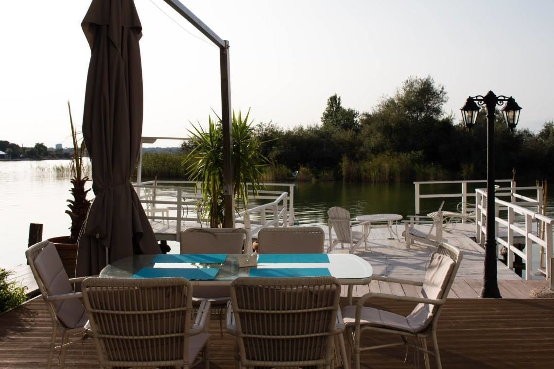 A deck with a table and chairs, overlooking a body of water.