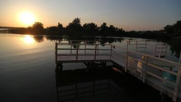 Un lac paisible au coucher du soleil, avec une jetée en bois et une petite table.