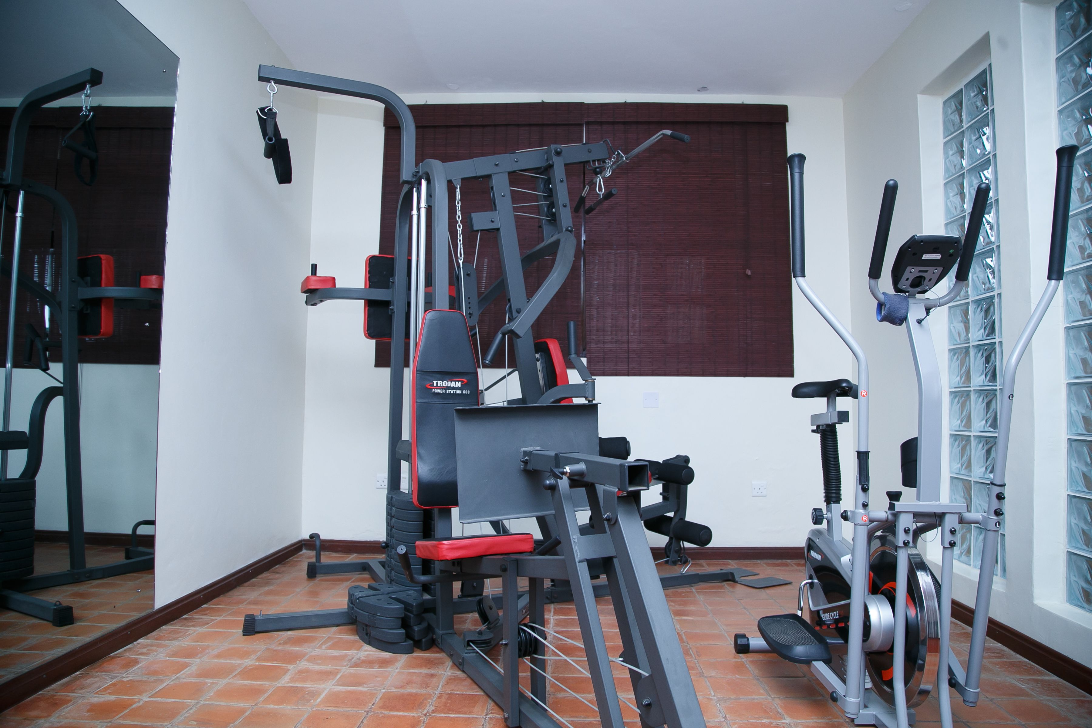 Een huisgym met een multifunctionele trainingsmachine, een hometrainer en een loopband.