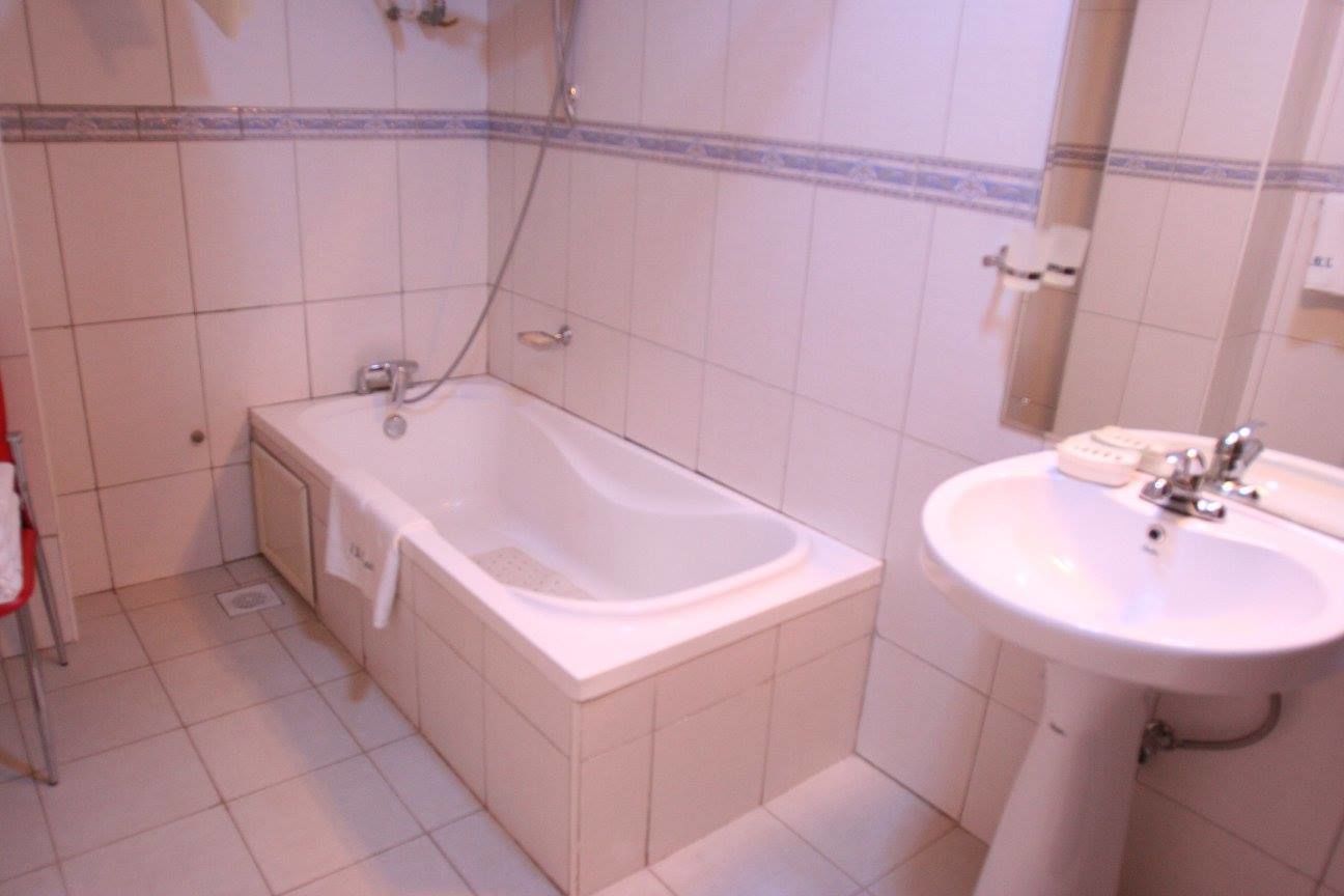 A bathroom with a bathtub, a sink, and a mirror.