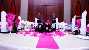 A table set for a formal event with pink and white decorations, including rose petals and napkins. - JBK Hotel (Kampala)