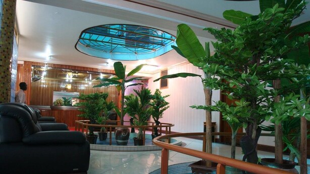 A lobby with a reception desk, seating area, and a central water feature. - JBK Hotel (Kampala)