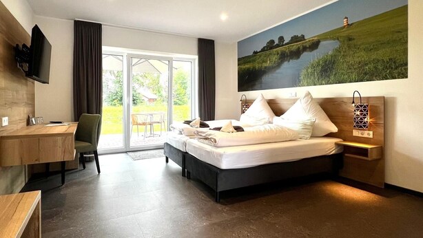 A modern hotel room with a large bed, a desk, and a television. - Hotel Zum großen Krug (Wirdum)