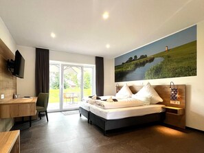 Ein modernes Hotelzimmer mit einem großen Bett, einem Schreibtisch und einem Fernseher.