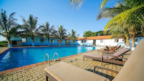 Une piscine avec des chaises longues et des palmiers.
