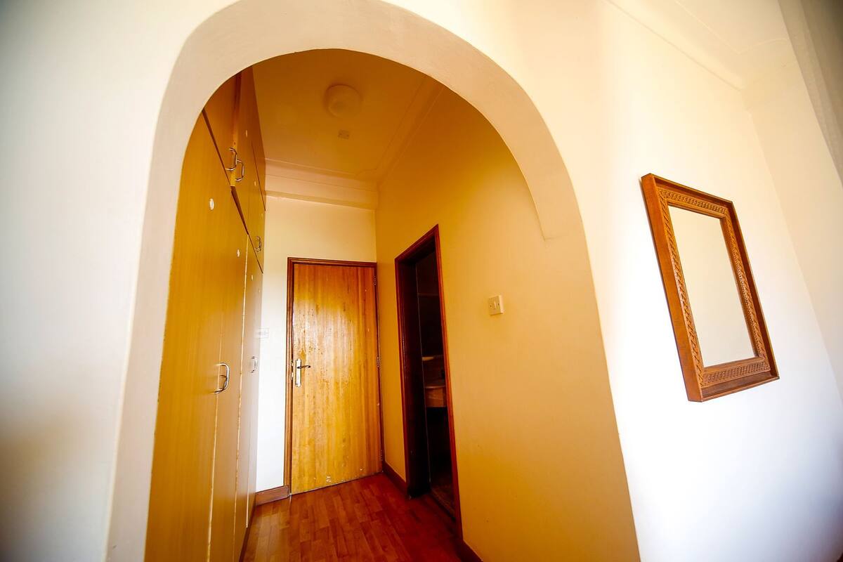 A hallway with an arched doorway, wooden doors, and a framed mirror on the wall.