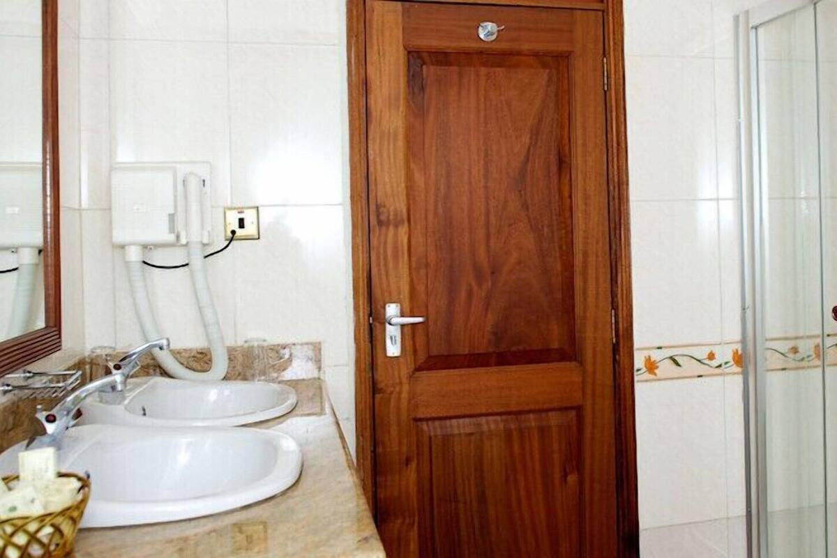 A bathroom with a wooden door, a sink with a mirror, and a shower with glass doors.
