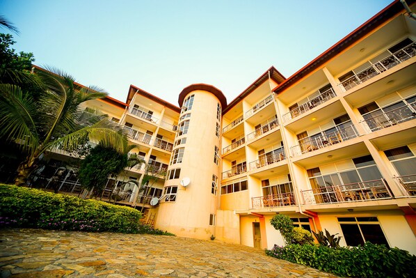 A multi-story hotel with balconies, a central tower, and a cobblestone courtyard.