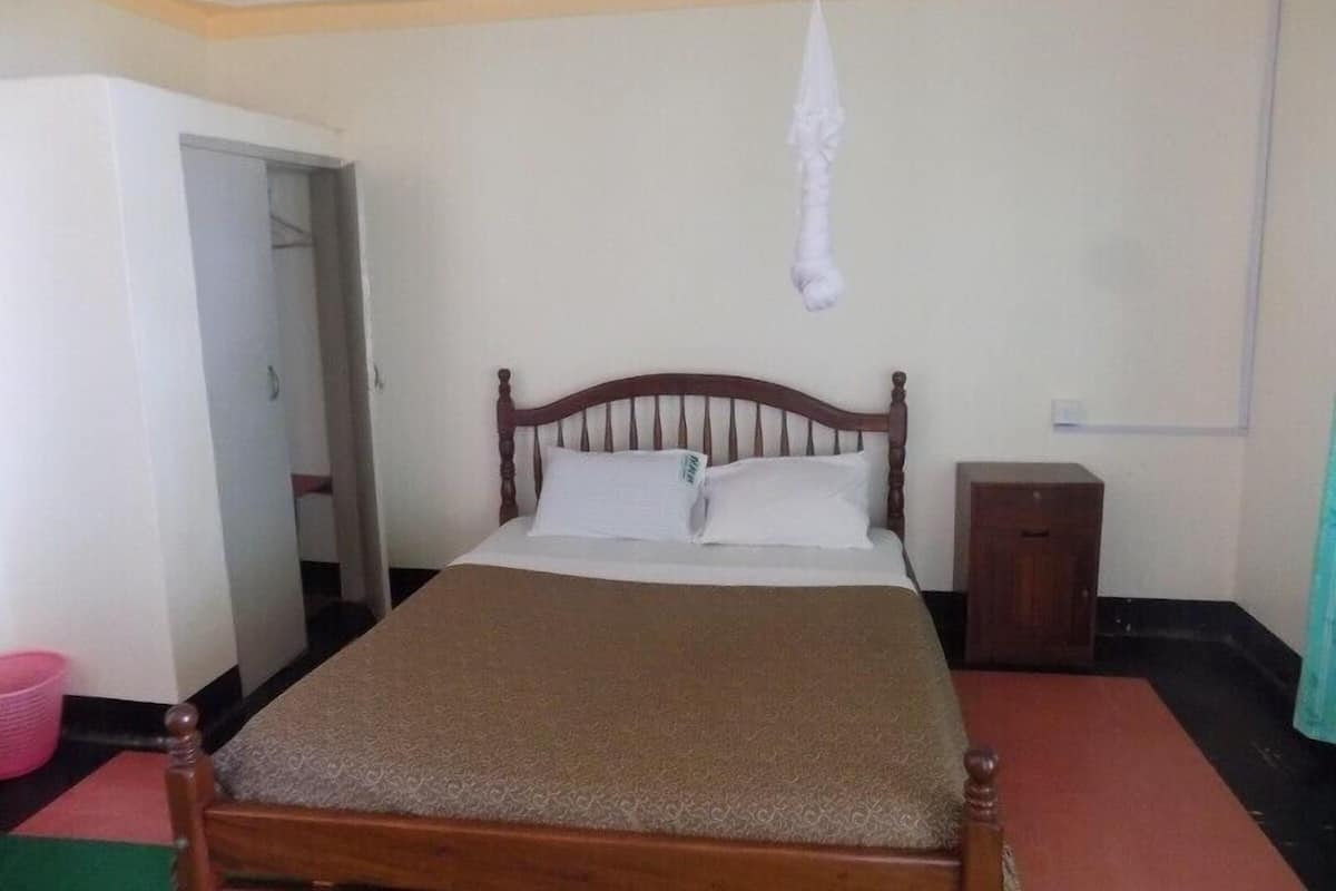 Una cama individual con cabecera de madera, una mesita de noche y un objeto blanco colgante.