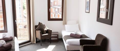 Habitación de hotel con cama, dos sillones, sofá, una mesita y una ventana con cortinas.