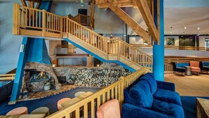 A multi-level wooden staircase with a fireplace at the bottom. - Hôtel Le Montana (Courchevel)