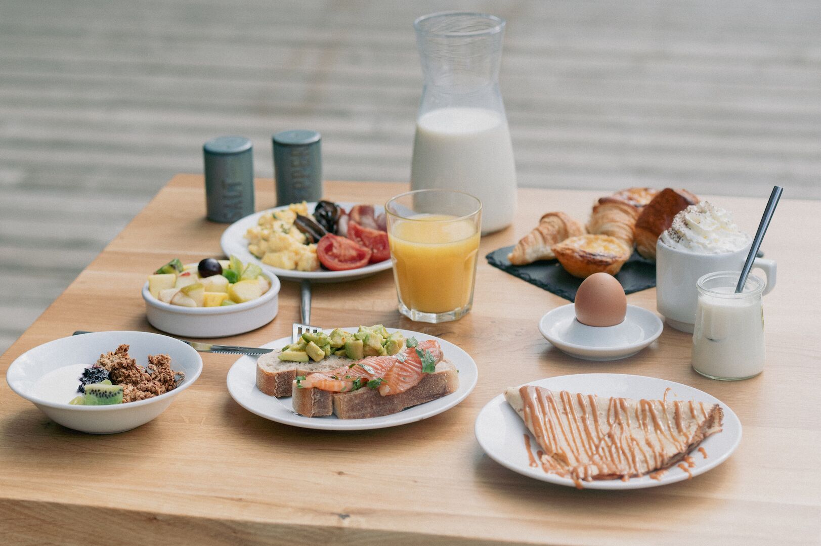 Ett frukostbord med olika rätter, inklusive rostat bröd, frukt, ägg och drycker.