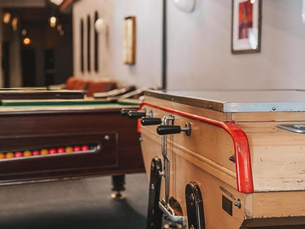 A pool table with a wooden side table and a red edge.
