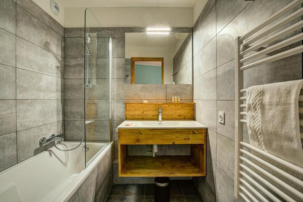 A modern bathroom with a glass-enclosed shower, a wooden vanity, and a towel rack.