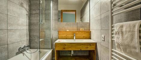 A modern bathroom with a glass-enclosed shower, a wooden vanity, and a towel rack.