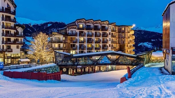 A multi-story hotel with balconies, a covered walkway, and snow-covered surroundings. - Hôtel Le Montana (Courchevel)