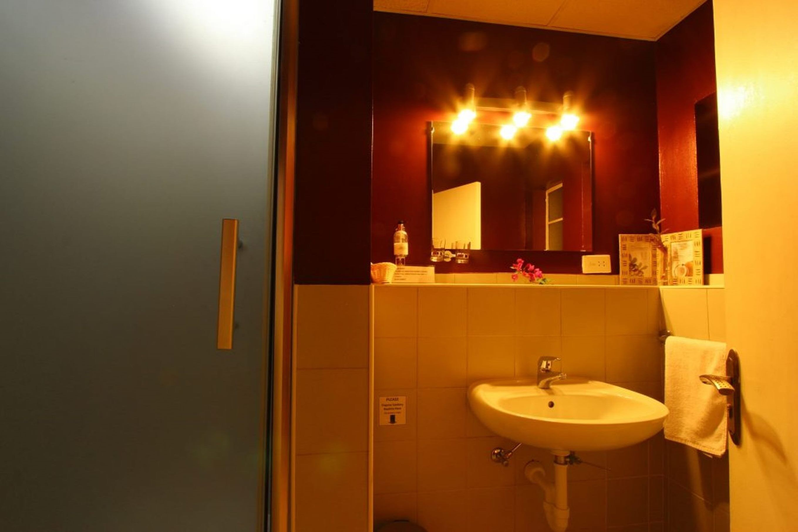 Un baño con lavamanos, espejo y una toalla colgada en la pared.