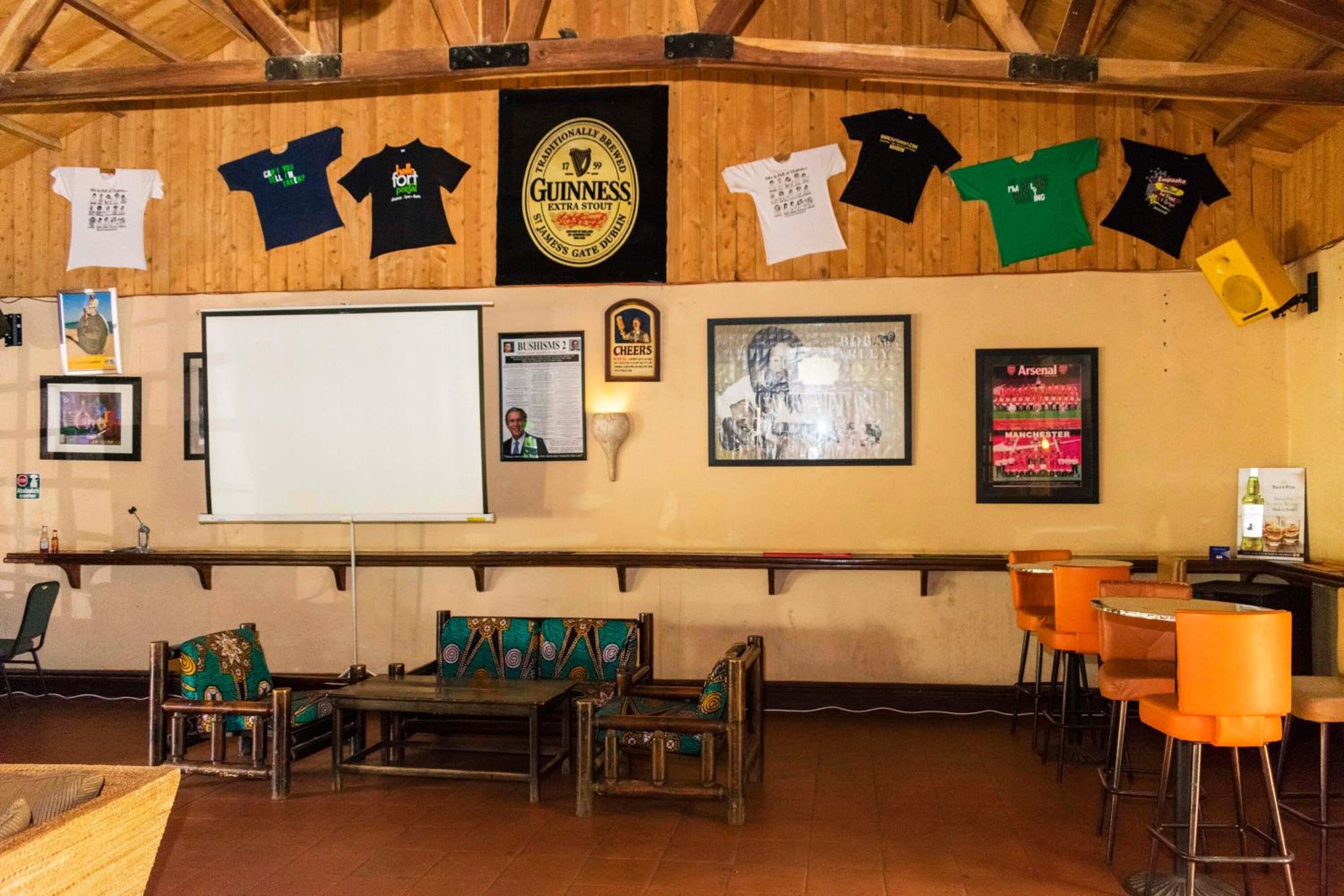 A pub with wooden walls, a large screen, and various framed pictures and posters.
