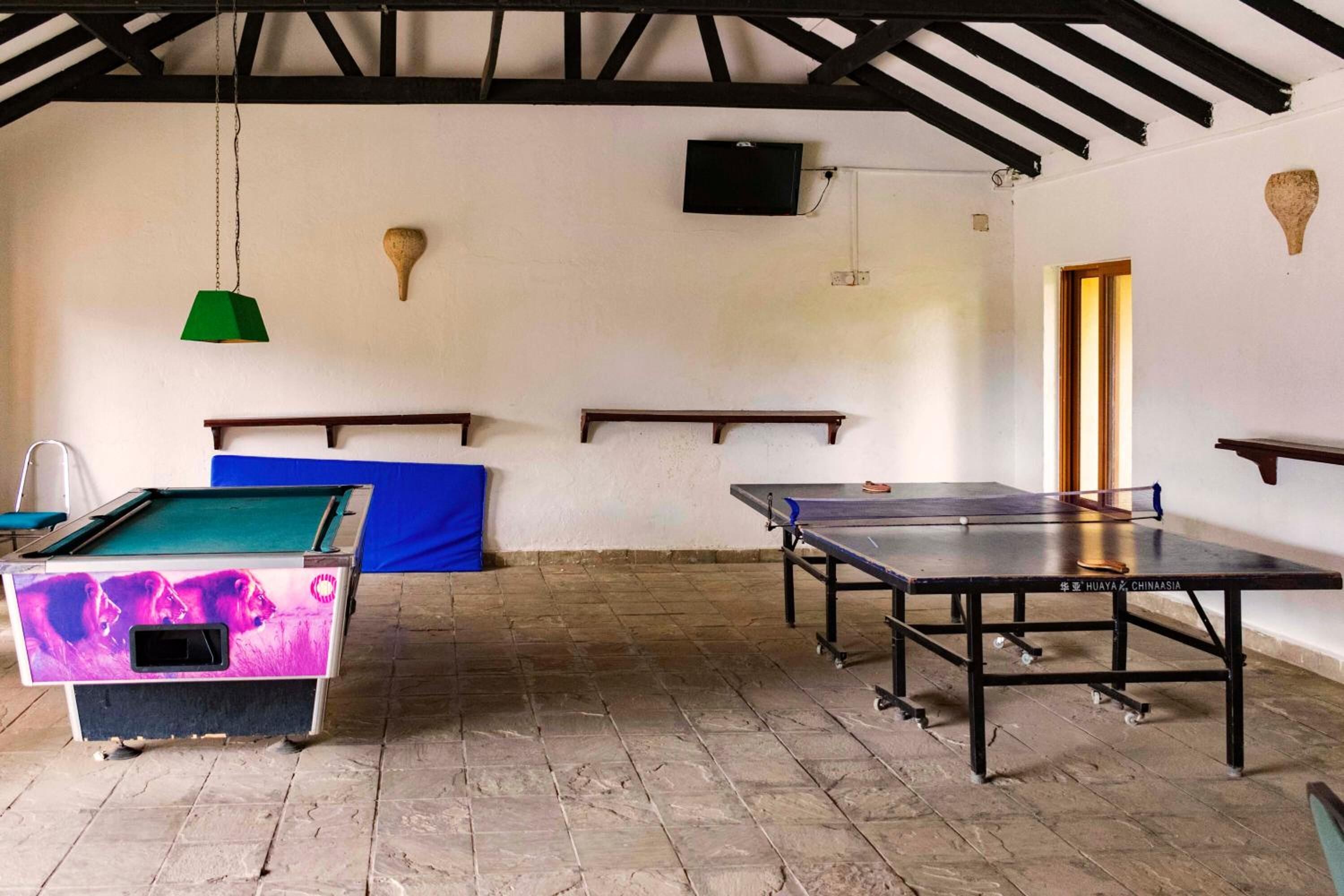 A billiards room with a pool table, a ping pong table, and a billiards table.