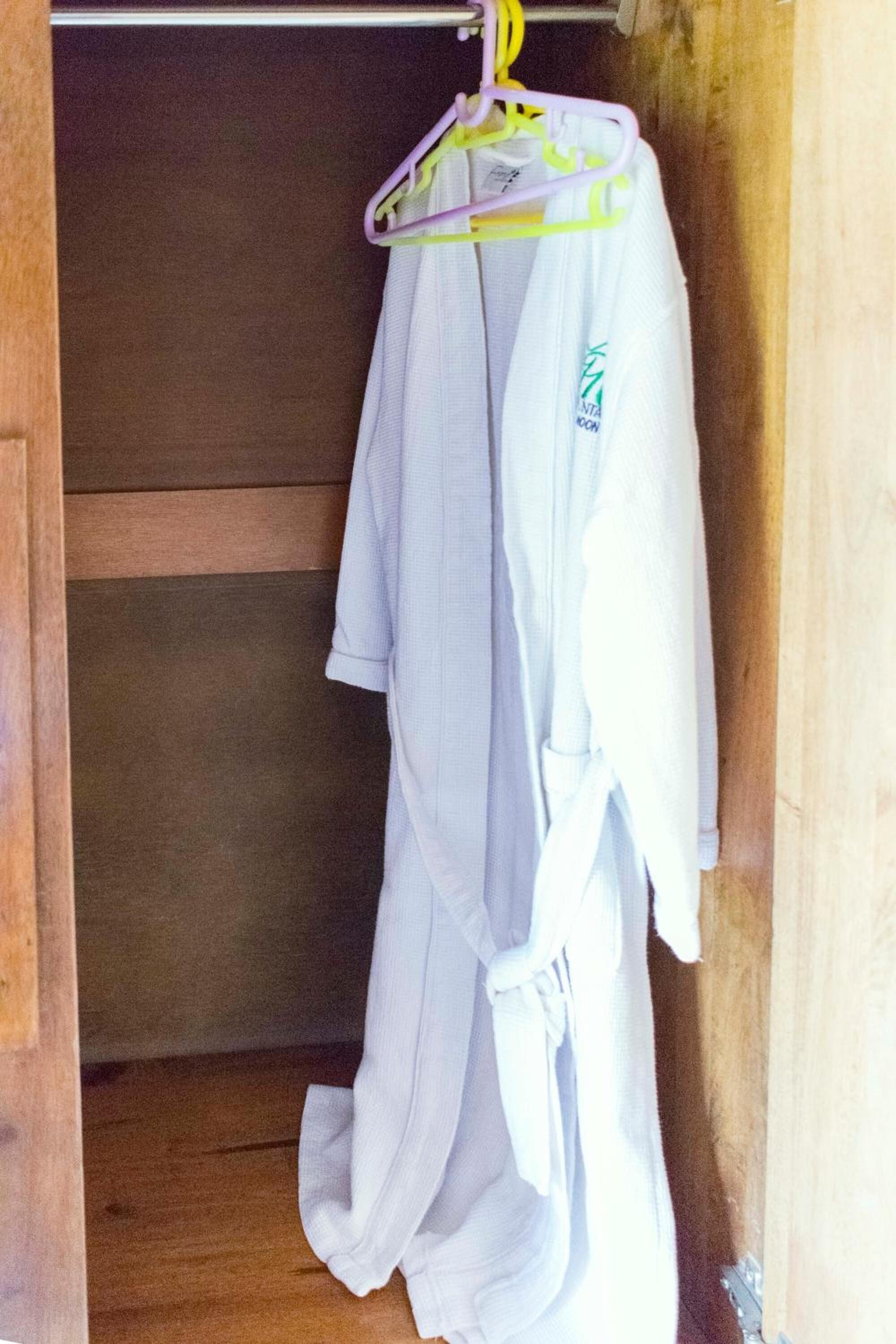 Ein Holzkoffer mit einem weißen Bademantel an einem Kleiderbügel.