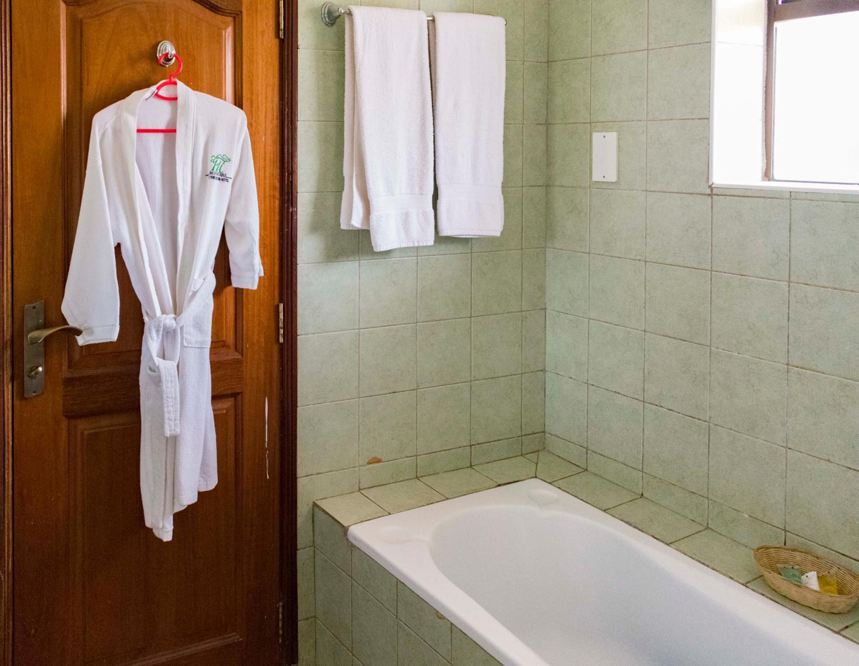 Ein Badezimmer mit Holztür, freistehender Badewanne und grünen Fliesen.