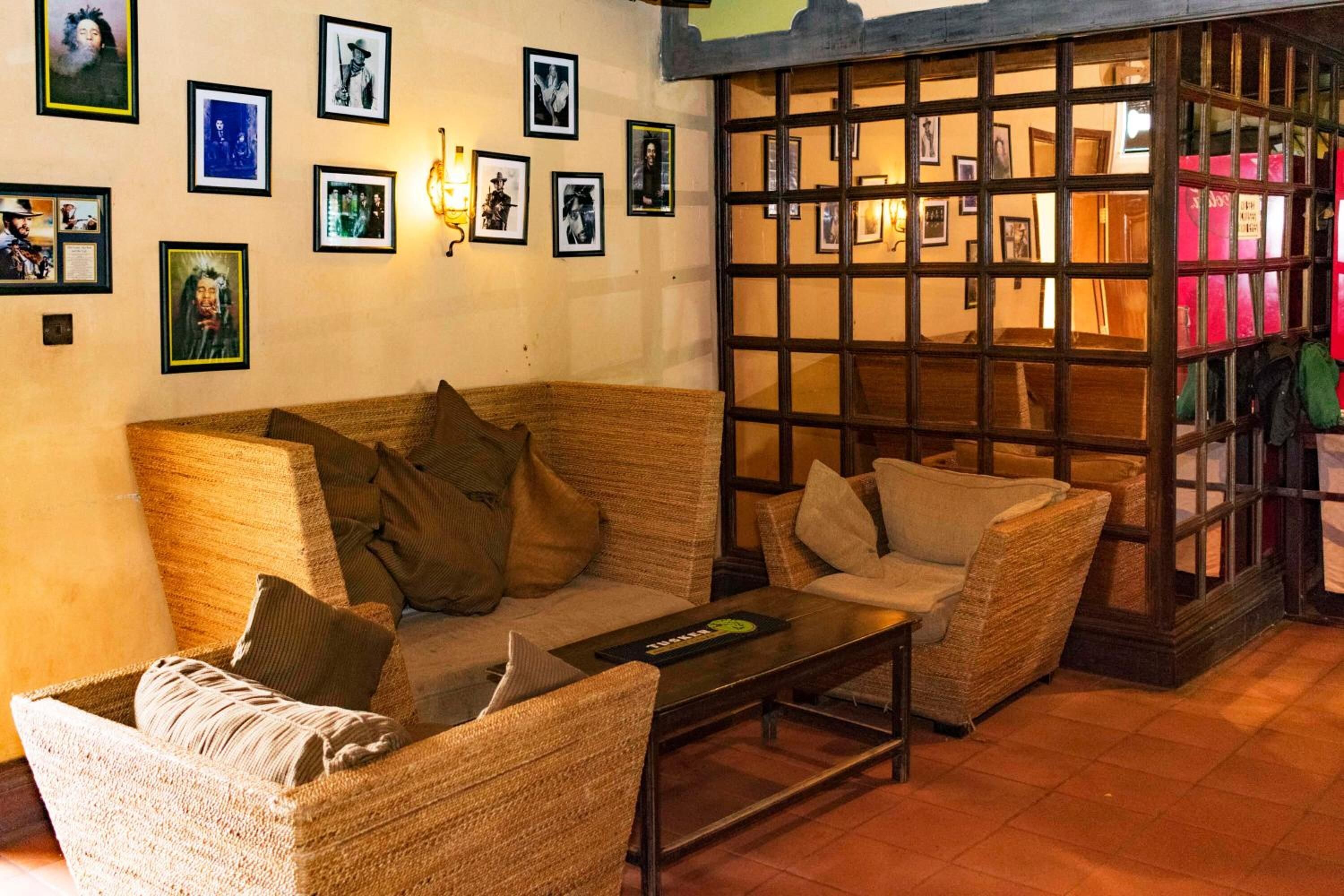 A cozy room with a woven sofa, a small table, and a wooden partition with framed pictures.