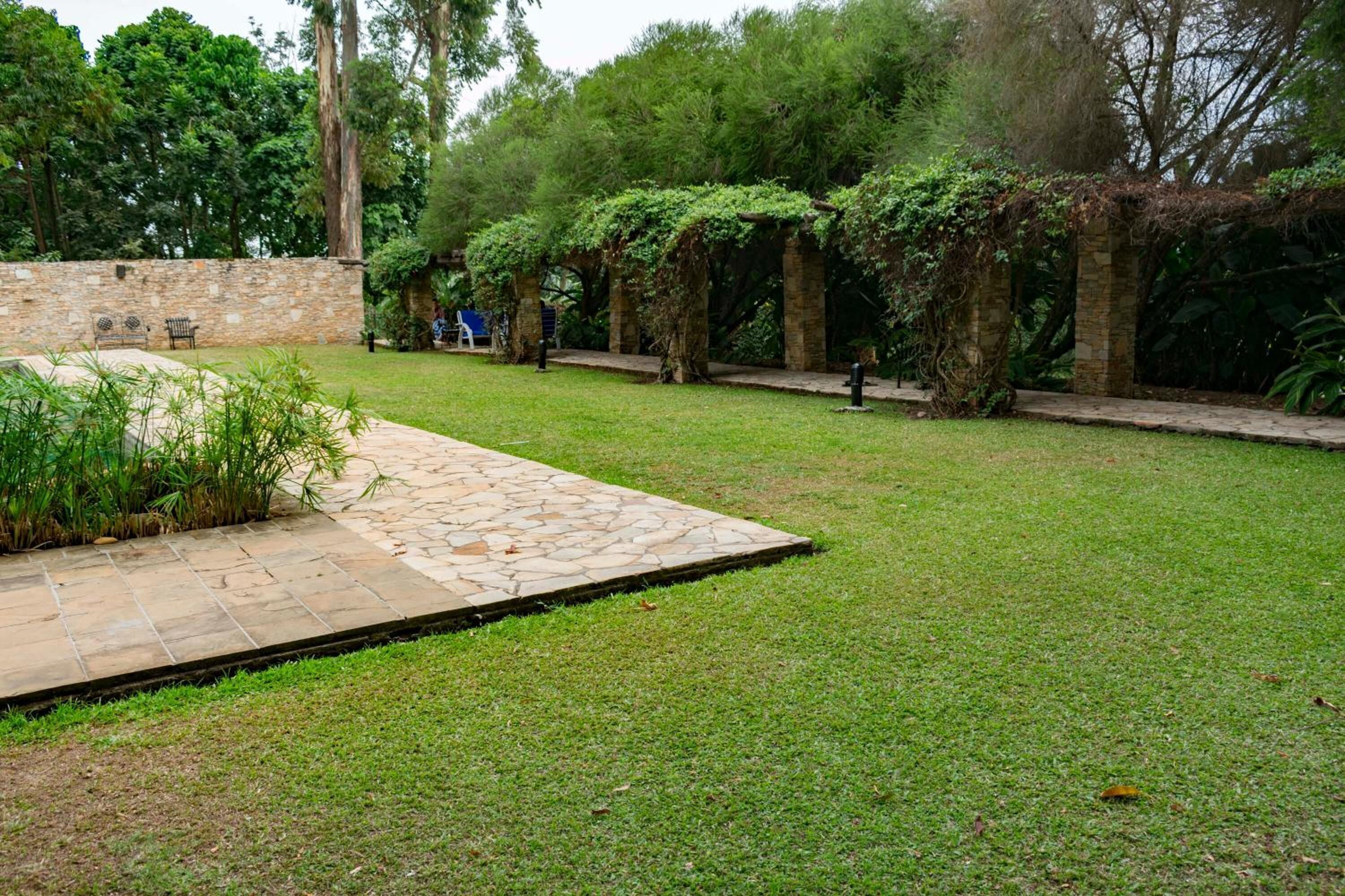 A stone pathway leading to a seating area with a stone wall and greenery.