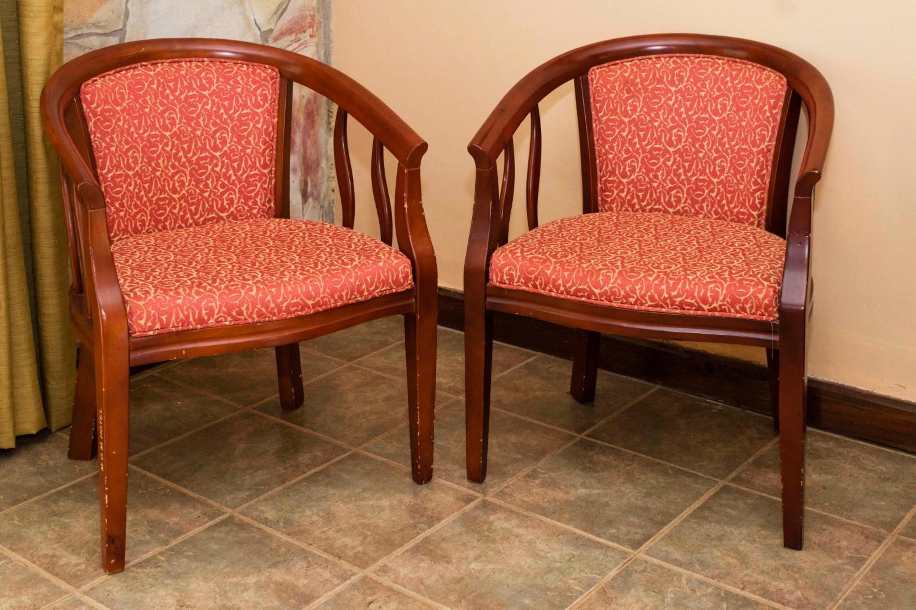 Two wooden chairs with red patterned upholstery.