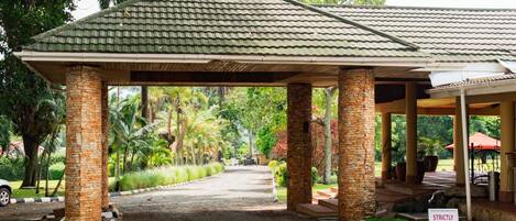 A covered pavilion with stone pillars, a gravel driveway, and a 'Strictly No Parking' sign.