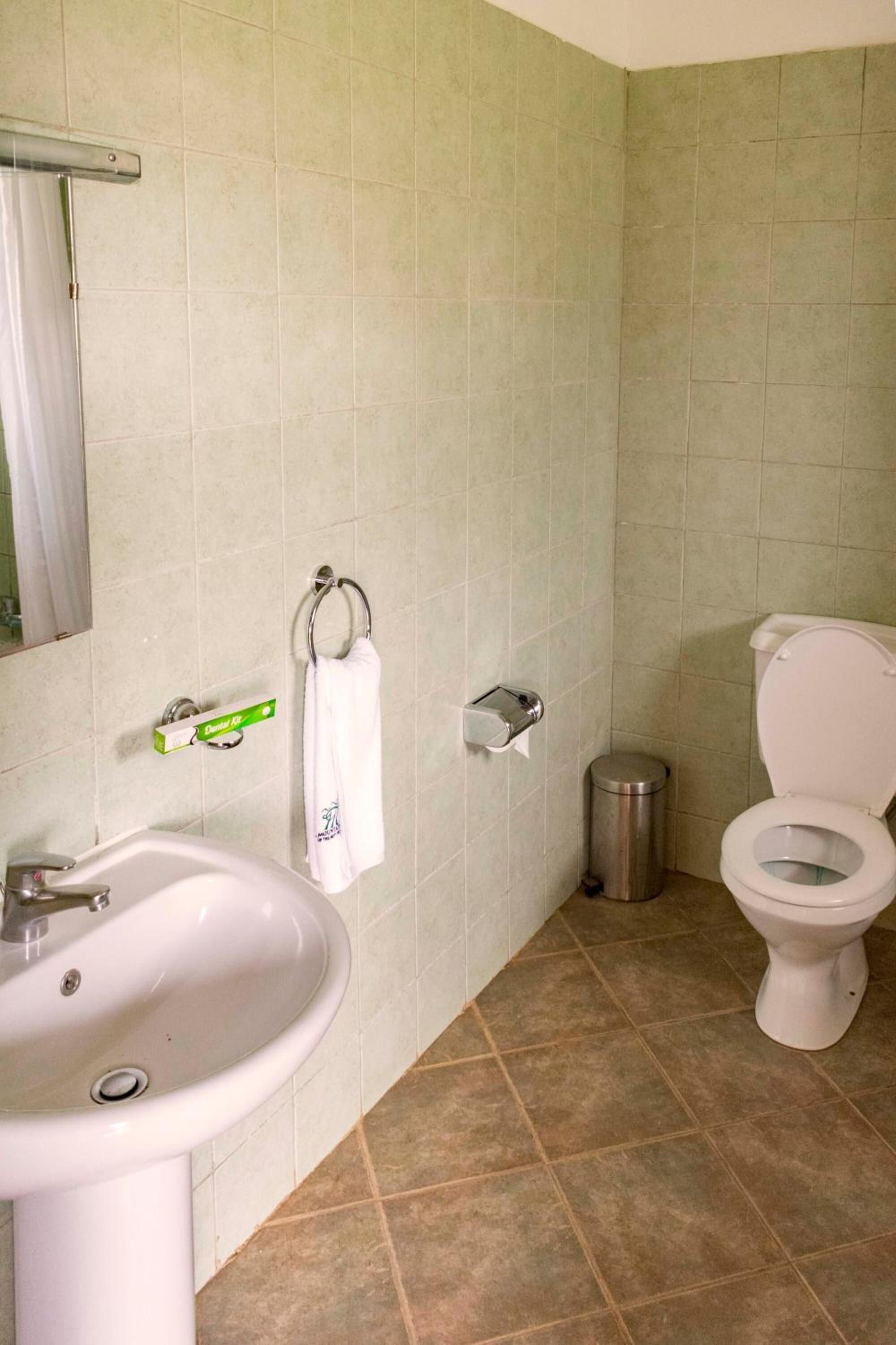 Une salle de bain avec un lavabo, des toilettes et une poubelle.