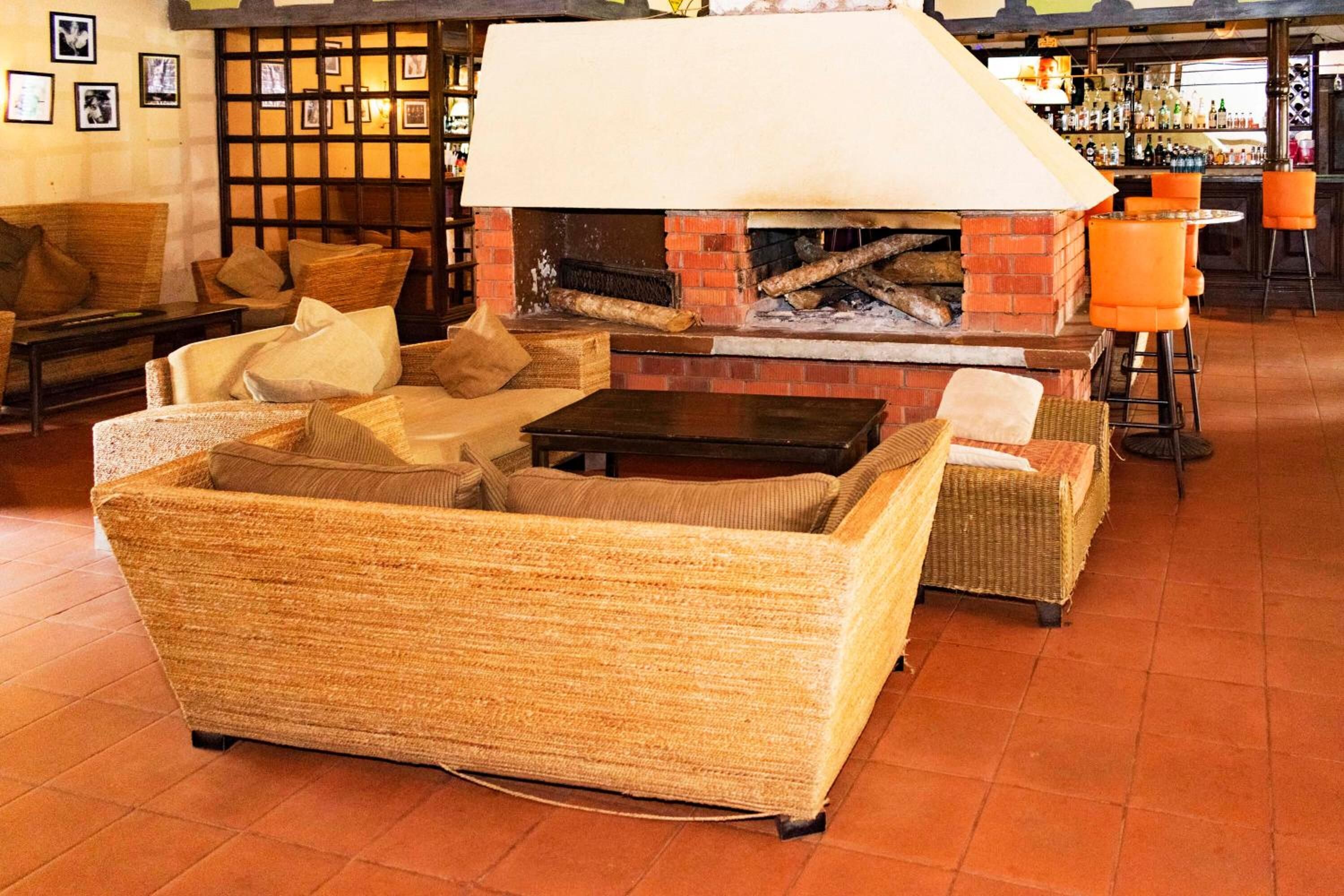A cozy lounge area with wicker furniture, a brick fireplace, and a bar with stools.
